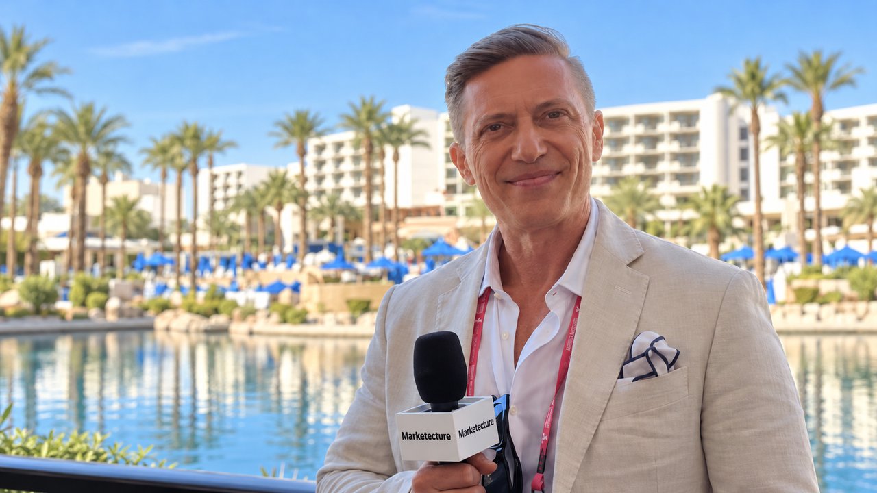 Evgeny Popov holding a Marketecture Media microphone at IAB ALM 2026, with a resort lagoon and palm trees behind him